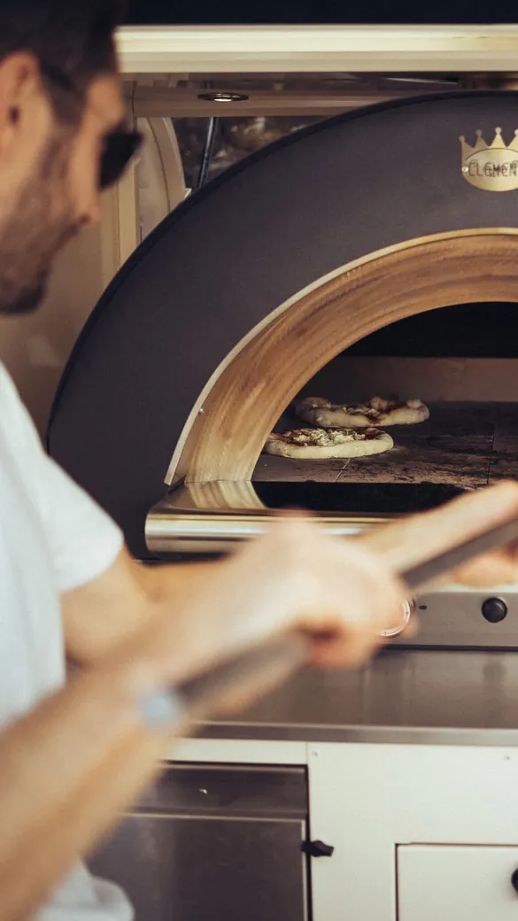 Pizza wird mit dem Schieber aus dem Ofen geholt